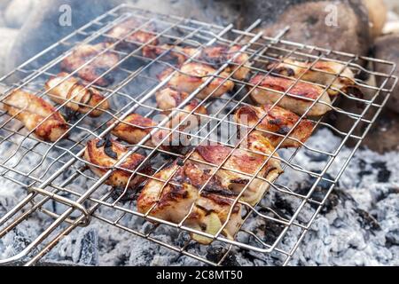 Saftige Fleischsteaks über Holzkohle auf einem Drahtgitter gekocht. Picknick in der Natur. Fleisch auf einem Feuer in der freien Luft gekocht. Selektiver Fokus. Nahaufnahme. Stockfoto