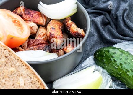 Gegrilltes Fleisch saftige Stücke über Holzkohle gekocht. Fleisch in einer Schüssel mit frischem Gemüse und Brot. Picknick in der Natur. Selektiver Fokus. Nahaufnahme. Stockfoto