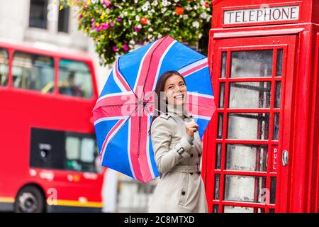 London Tourist Travel Frau mit britischen Flagge Regenschirm, Telefonbox, rot großen Bus. Europa Reiseziel Asiatisches Mädchen mit britischen Ikonen, rote Phonebox Stockfoto