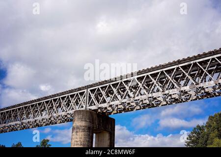 Eine Eisenbahnbrücke aus Beton und Stahl gegen einen wolkigen blauen Himmel Stockfoto