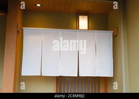 Der Vorhang-ähnliche Stoff, der vor traditionellen japanischen Restaurants und Geschäften hängt, dient nicht nur als Schild, sondern hat eine größere Bedeutung, Stockfoto