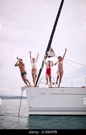 Freunde springen an einem sonnigen Tag von einer Yacht ins Meer Stockfoto