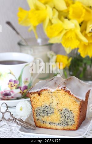 Karotten-Mohn-Kuchen und Tasse Tee als Frühlingstisch Dekoration Stockfoto
