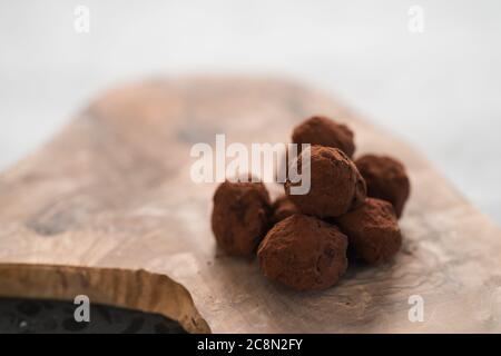 Handgemachte Schokoladentrüffel auf olivfarbenem Brett Stockfoto