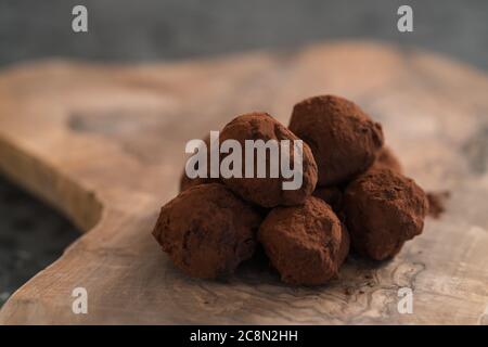 Handgemachte Schokoladentrüffel auf olivfarbenem Brett Stockfoto