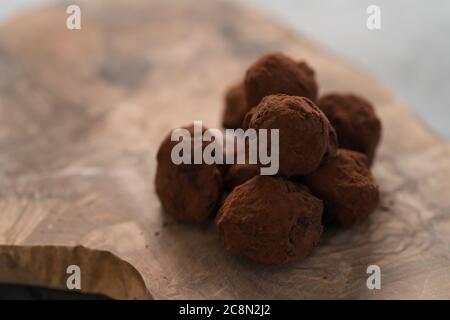 Handgemachte Schokoladentrüffel auf olivfarbenem Brett Stockfoto
