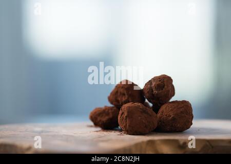 Handgemachte Schokoladentrüffel auf olivfarbenem Brett Stockfoto