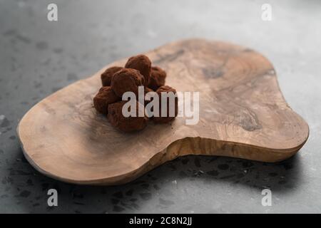 Handgemachte Schokoladentrüffel auf olivfarbenem Brett Stockfoto