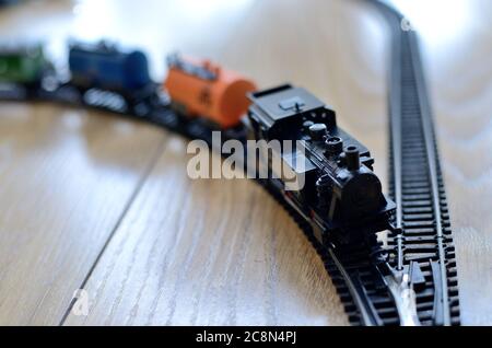 Miniatur-Spielzeugzug, schwarze Lokomotive mit Autos auf Metallschienen, Maßstab 1:120. Vintage Spielzeug aus den 80ern. Stockfoto