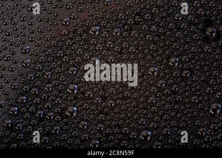 Viele kleine Wassertropfen auf der schwarzen Oberfläche des Mobiltelefons Hydrophober beschichteter Glasschirm Stockfoto