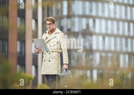 Weitwinkel-Porträt von eleganten jungen Geschäftsmann trägt Trenchcoat beim Lesen von Dokumenten im Freien in der Stadt Einstellung, kopieren Raum Stockfoto