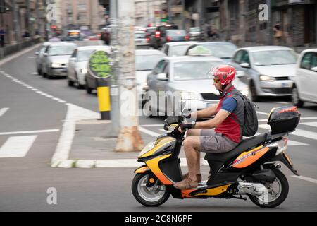 Belgrad, Serbien - 16. Juli 2020: Reifer Mann auf einem Motorroller im Stadtverkehr, auf der Kreuzung mit Autos in der Schlange Stockfoto