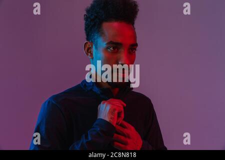 Portrait von bärtigen afrikanische amerikanische Mann in Sportswear poising an Kamera über violett Hintergrund isoliert Stockfoto