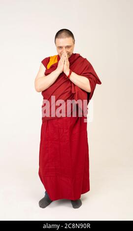 lama Mönch faltete seine Handflächen und rezitieren ein Mantra. Monakh ist in einem roten Lama-Outfit gekleidet Stockfoto