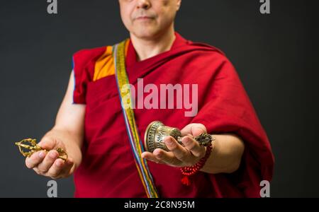 Träger eines buddhistischen Mönchs in einem Lama-Kleid. Der Mönch hält die rituellen Attribute des Buddhismus, Rosenkranz, Vajra, Glocke Stockfoto