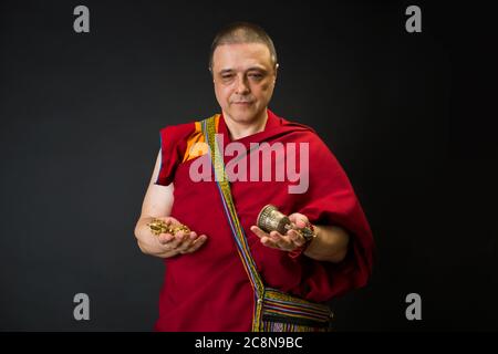 Träger eines buddhistischen Mönchs in einem Lama-Kleid. Der Mönch hält die rituellen Attribute des Buddhismus, Rosenkranz, Vajra, Glocke Stockfoto