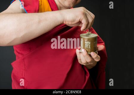 Der Mönch hält eine Gebetstrommel in der Hand. Porträt eines buddhistischen Mönchs in roten Kleidern. Stockfoto