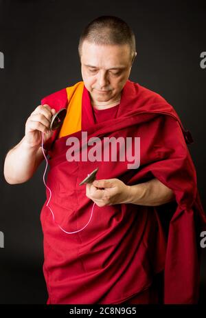 Der Mönch hält eine Gebetstrommel in der Hand. Porträt eines buddhistischen Mönchs in roten Kleidern. Stockfoto