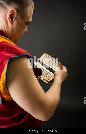 Buddhistischer Mönch in rotem Kleid mit Gebetstexten und Mantras in der Hand Stockfoto