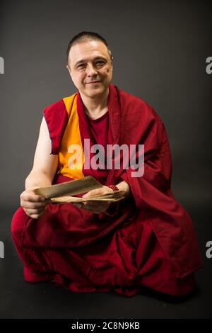 Buddhistischer Mönch in rotem Kleid mit Gebetstexten und Mantras in der Hand Stockfoto