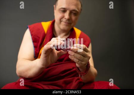 Uddhistischer Mönch in rotem Kleid, einen Kristall aus Glas in der Hand haltend Stockfoto