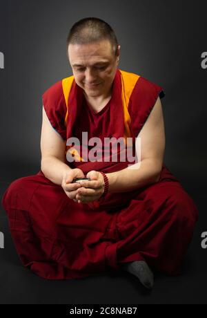 Uddhistischer Mönch in rotem Kleid, einen Kristall aus Glas in der Hand haltend Stockfoto