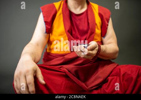 Uddhistischer Mönch in rotem Kleid, einen Kristall aus Glas in der Hand haltend Stockfoto