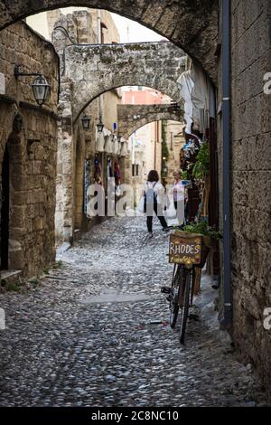 Selektiver Fokus auf ein Fahrrad unter den gewölbten Strebepfeilern in den mittelalterlichen Kopfsteinpflasterstraßen der Altstadt von Rhodos, Insel Rhodos, Griechenland Stockfoto