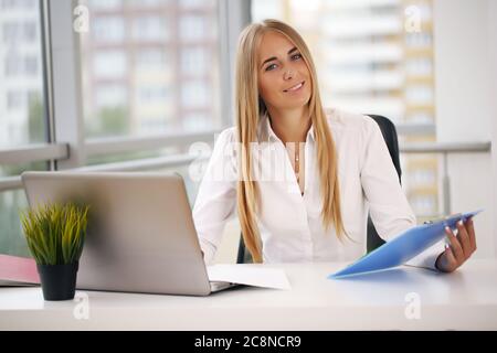 Blonde lächelnde Chats am Telefon im Büro Stockfoto