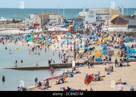 Lyme Regis, Dorset, Großbritannien. Juli 2020. UK Wetter: Urlauber strömen an einem Tag mit heißen Sonneneinschlägen und Regenschauern zum Strand von Lyme Regis. Kredit: Celia McMahon/Alamy Live Nachrichten Stockfoto