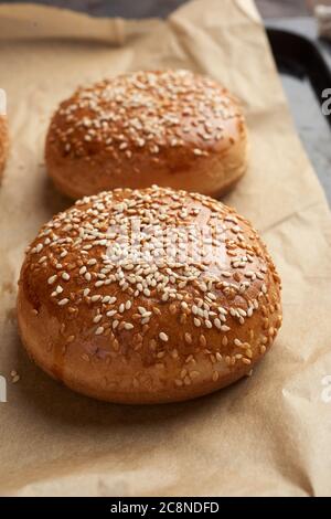 Gebackene Sesambrötchen auf braunem Pergamentpapier, Zutat für einen Hamburger, Nahaufnahme Stockfoto