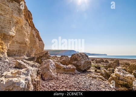 Felsen unter den Klippen von Hope Gap in Sussex, mit den Seven Sisters Klippen in der Ferne Stockfoto