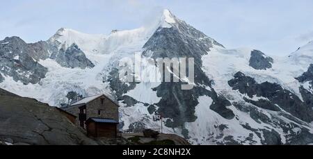 Panoramablick auf idyllische Bergkulisse in den Alpen mit einsames traditionelles Bergchalet an wolkig kalten Tagen. Schöne wilde felsige Natur, ruhige Atmosphäre. Berggipfel Ober Gabelhorn im Hintergrund Stockfoto