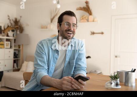 Lächelnder junger Mann schaut in der Ferne und spricht mit einem Freund Stockfoto