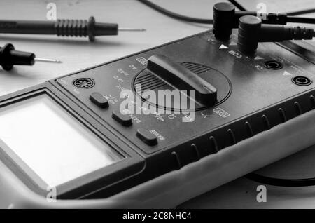 Nahaufnahme des Multimeters auf hellem Hintergrund. Detaillierte Aufnahme des Messgeräts. Qualifizierte Elektriker. Selektiver Fokus. Schwarzweiß Stockfoto