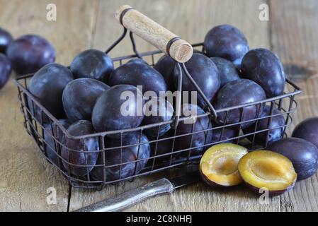 Frische Pflaumen im Korb auf Holztisch Stockfoto