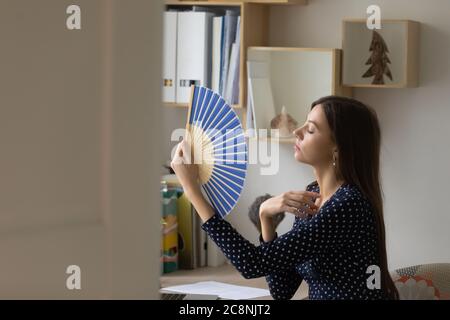 Unwohl junge Frau winkt mit Handventilator zu Hause Stockfoto