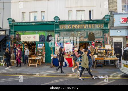 Besucher der Portobello Road, Notting Hill, London, Bummeln und Stöbern. Britische Flagge und Lord Kitchener Poster in der Mitte des Bildes. Stockfoto