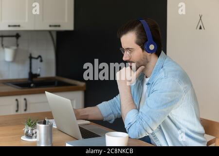 Millennial man in headphones Webinar auf Laptop ansehen Stockfoto
