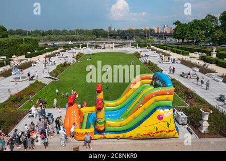 WARSCHAU, POLEN - 2. JUNI 2019: Menschen mit kleinen Kindern, Kinder spielen und Spaß an der riesigen aufblasbaren Rutsche in den Gärten des königlichen Schlosses Stockfoto