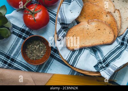 Natürliche frische Lebensmittel, italienische vegetarische Zutaten, Spaghetti mit Knoblauch und Brot Toast auf einem Korb auf Tischtuch, grüne Pfeffer Holzgabel Stockfoto