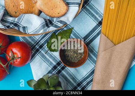 Natürliche frische Lebensmittel, italienische vegetarische Zutaten, Spaghetti mit Knoblauch und Brot Toast auf einem Korb auf Tischtuch, grüne Pfeffer Holzgabel Stockfoto