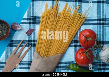 Natürliche frische Lebensmittel, italienische vegetarische Zutaten, Spaghetti mit Knoblauch und Brot Toast auf einem Korb auf Tischtuch, grüne Pfeffer Holzgabel Stockfoto