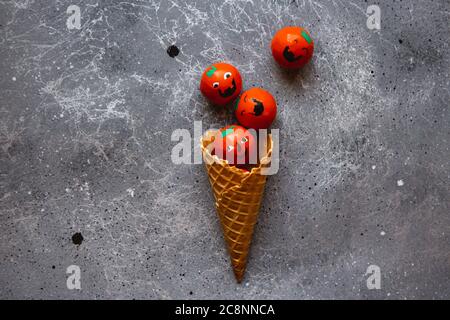 Waffelkegel ist mit Süßigkeiten Halloween Kürbisse auf dem grauen Hintergrund gefüllt Stockfoto