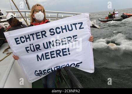 Sassnitz, Deutschland. Juli 2020. Greenpeace-Aktivisten versenken große Granitblöcke vom Greenpeace-Schiff "Beluga II" vor der Ostseeinsel Rügen ins Meer. Eine Frau hält ein Banner mit der Aufschrift "echter Schutz für unsere Meere! Greenpeace“ in die Kamera. Mit dieser Aktion im Meeresschutzgebiet Adlergrund wollen die Umweltschützer verhindern, dass der Boden von Fischern mit Schleppnetzen "durchgepflügt" wird. Quelle: Stefan Sauer/dpa/Alamy Live News Stockfoto