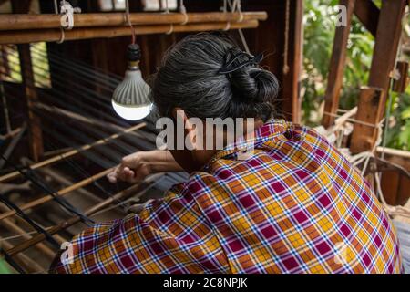 Inle Lake, Myanmar - Februar 2020: Asiatische Frau webt Stoff auf einem traditionellen Holzwebstuhl im Dorf. Stockfoto