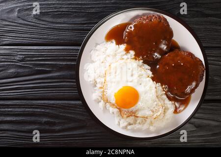 Loco Moco Rezept ist ein köstliches hawaianisches Gericht besteht aus weißem Reis, einem saftigen Hamburger Patty, einem Spiegelei und brauner Soße Nahaufnahme auf einem Teller auf dem Stockfoto