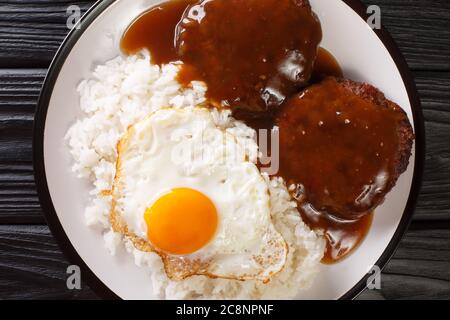 Das klassische hawaiianische Gericht Loco Moco besteht aus gedämpftem Reis mit saftigem Hamburger-Steak, Spiegelei und erstickt in einer würzigen Soße aus nächster Nähe auf einem Teller Stockfoto