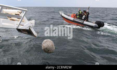 Sassnitz, Deutschland. Juli 2020. Ein Stein fällt in die Ostsee, während Greenpeace-Aktivisten des Greenpeace-Schiffes "Beluga II" vor der Insel Rügen große Granitblöcke ins Meer versenken. Ein Kameramann und ein Fotograf dokumentieren die Ereignisse von einem Greenpeace Schlauchboot aus. Mit der Aktion im Adlergrund Marine Reserve will Greenpeaee verhindern, dass der Boden von Fischern mit Schleppnetzen "durchgepflügt" wird. Quelle: Stefan Sauer/dpa/Alamy Live News Stockfoto