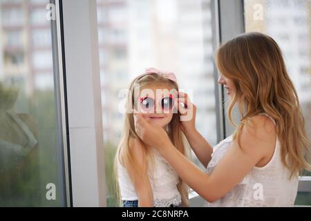 Mutter und ihr Baby spielen umarmt vor dem Hintergrund eines Panoramafensters Stockfoto